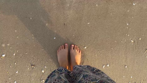 slim female legs and feet stand along sea water waves on sandy beach in doha qatar