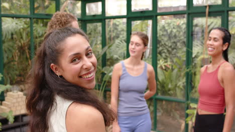 smiling woman in yoga attire with friends in glass house, enjoying conversation