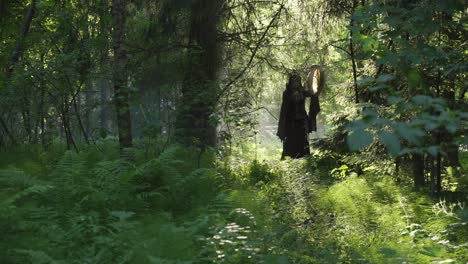 shaman stands in the forest and plays the drum