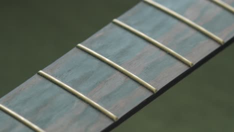 racking focus shot of frets on the wooden fingerboard of an acoustic guitar