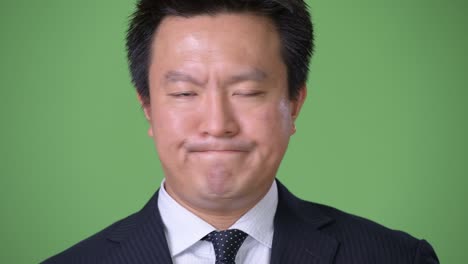 hombre de negocios japonés maduro contra un fondo verde