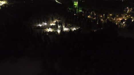 aerial view rotating toward a illuminated cabin village, winter night in finland