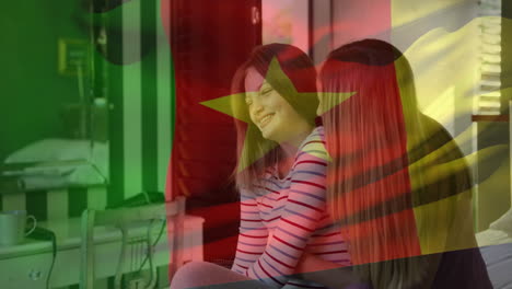 animation of flag of cameroon over caucasian mother and daughter brushing hair