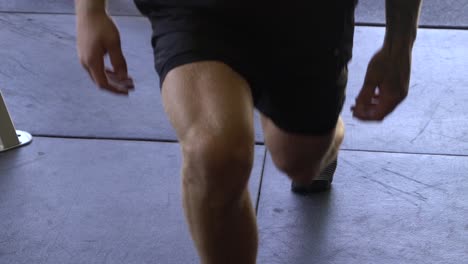 muscly man in home gym exercising static lunge leg muscles