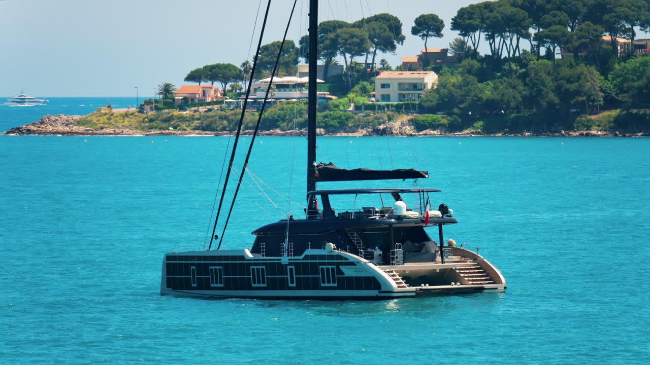 Antibes, France - May 24, 2025: Boat floating on the Mediterranean sea with villas surrounded by greenery in the background