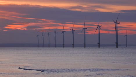 a wind farm generates electricity along a coastline at sunset 2