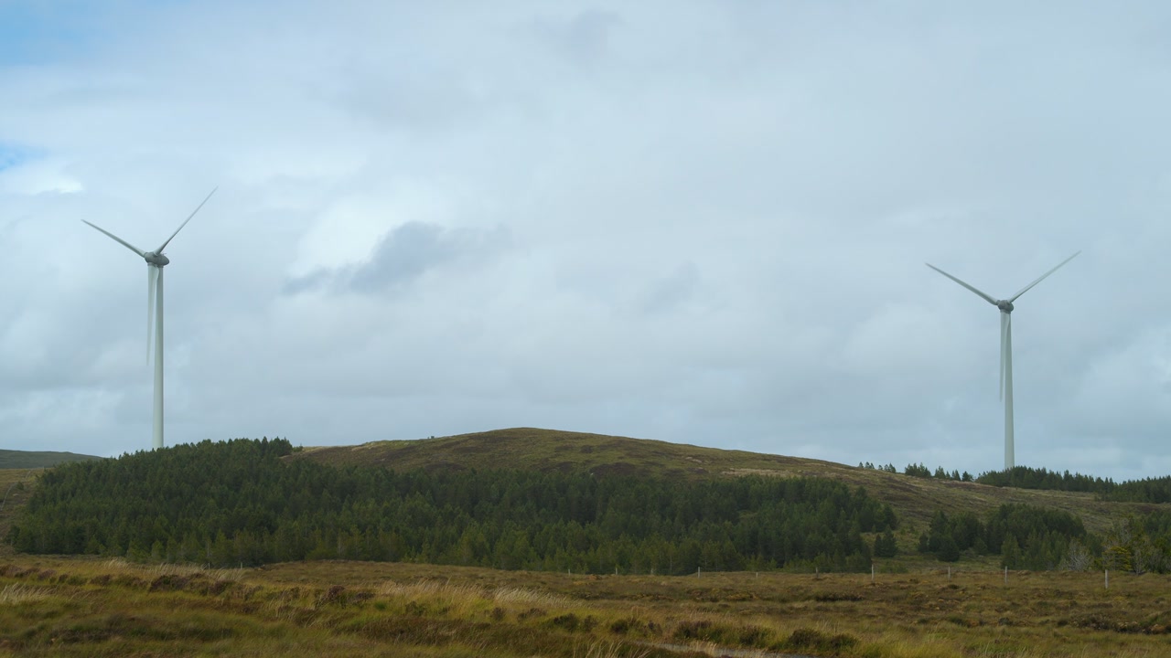 Static shot of an operational wind farm on a cloudy, Hebridean moor.