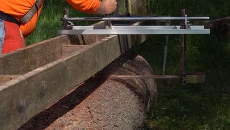 Rear-facing-medium-shot-of-logger-wearing-orange-using-alaskan-chainsaw-mill-on-pine-log-in-slow-motion