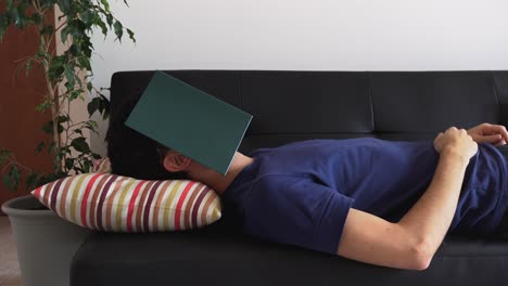 hombre acostado en el sofá durmiendo, con la cara cubierta por un libro