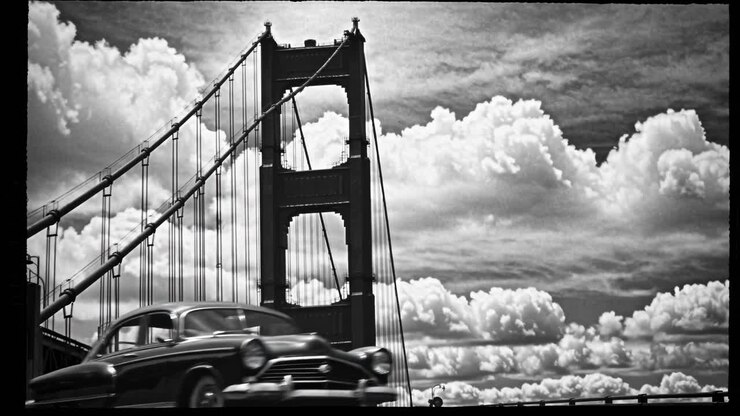 Black and white video frame of a bridge captured from a low angle, emphasizing its structure
