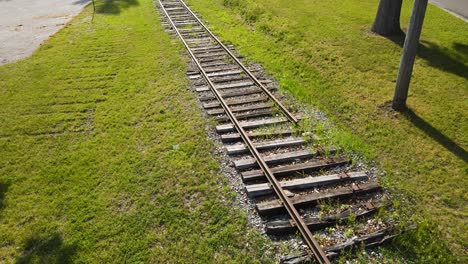 Erhebt-Sich-Und-Zeigt-Alte-Bahngleise-Bei-üppigem-Sommerwetter-In-Der-Nähe-Von-Stromleitungen