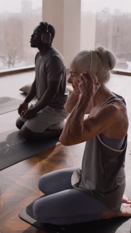 diverse group of people meditating or doing yoga in a studio.