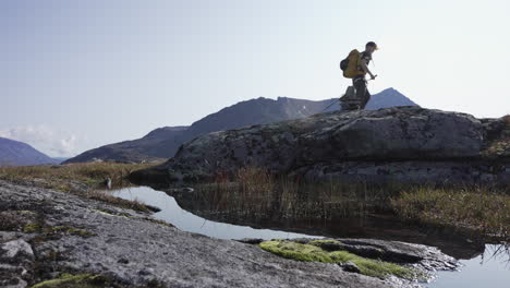 Low-angle-view-against-sun-of-male-hiking-flat-with-mountains-in-backgroud-during-early-sunny-autumn-morning