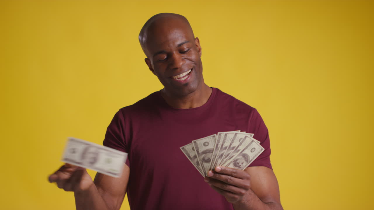 Studio Shot Of Excited Mature Man Celebrating Winning Cash Prize Kissing Counting And Throwing Handful Of 100 Dollar Bills In The Air