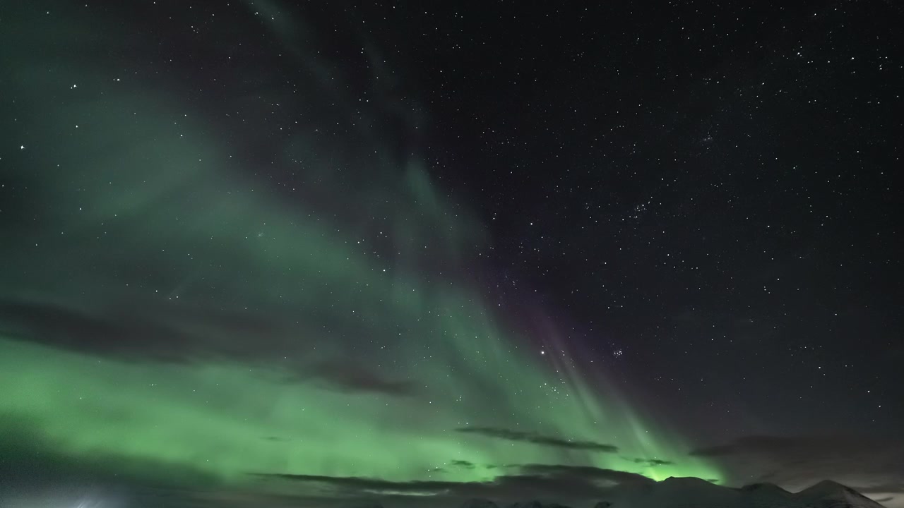 Aurora Boreale Vibrante che Danza su un Paesaggio Montano Innevato di Notte