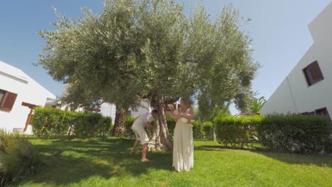 happy parents and children in green garden with big olive tree