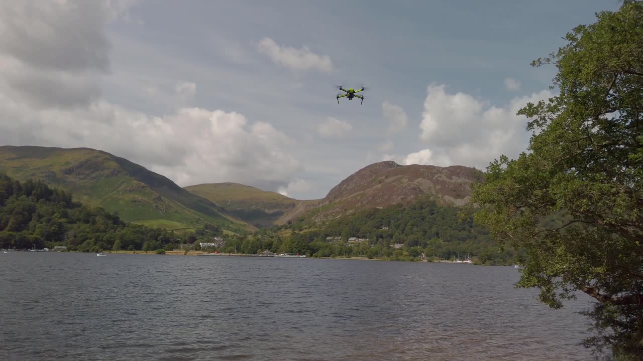 글렌리딩 마을 근처 호수 지구 국립공원의 울스워터 위로 날아다니는 작은 드론, 레이크랜드 폭포와 흐린 하늘을 배경으로