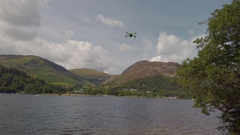 small drone flying over ullswater in the lake district national park near the village of glenridding, with the lakeland fells and a cloudy sky in the background