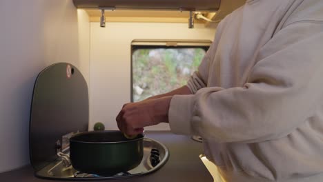 woman cutting potatoes by hand and dropping them in cooking pot inside camper