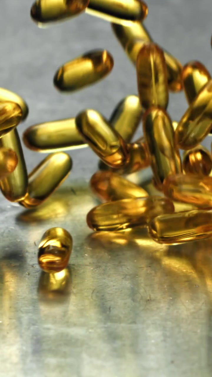 Capsule softgel di Omega 3 dorate che cadono al rallentatore