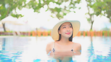 beautiful exotic woman in swimming pool with floppy hat, close up, slow motion