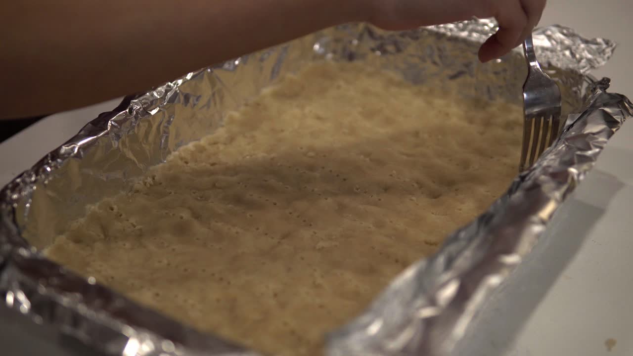 una niña airea la corteza en una bandeja para hornear para hacer galletas de mantequilla millonarias