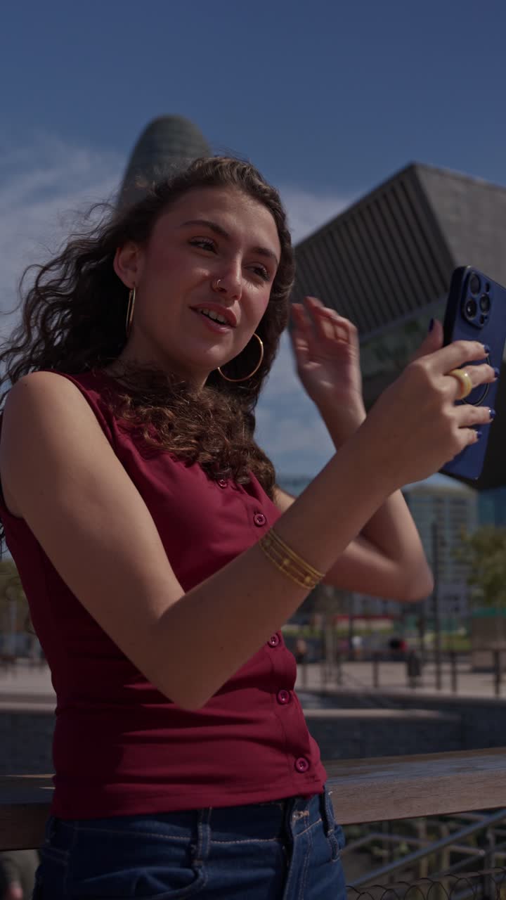Giovane donna felice in videochiamata con lo smartphone in città
