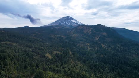 Descending-drone-shot-of-volcanic-fumarole-at-Popocatepetl-in-Mexico-and-surrounding-forest