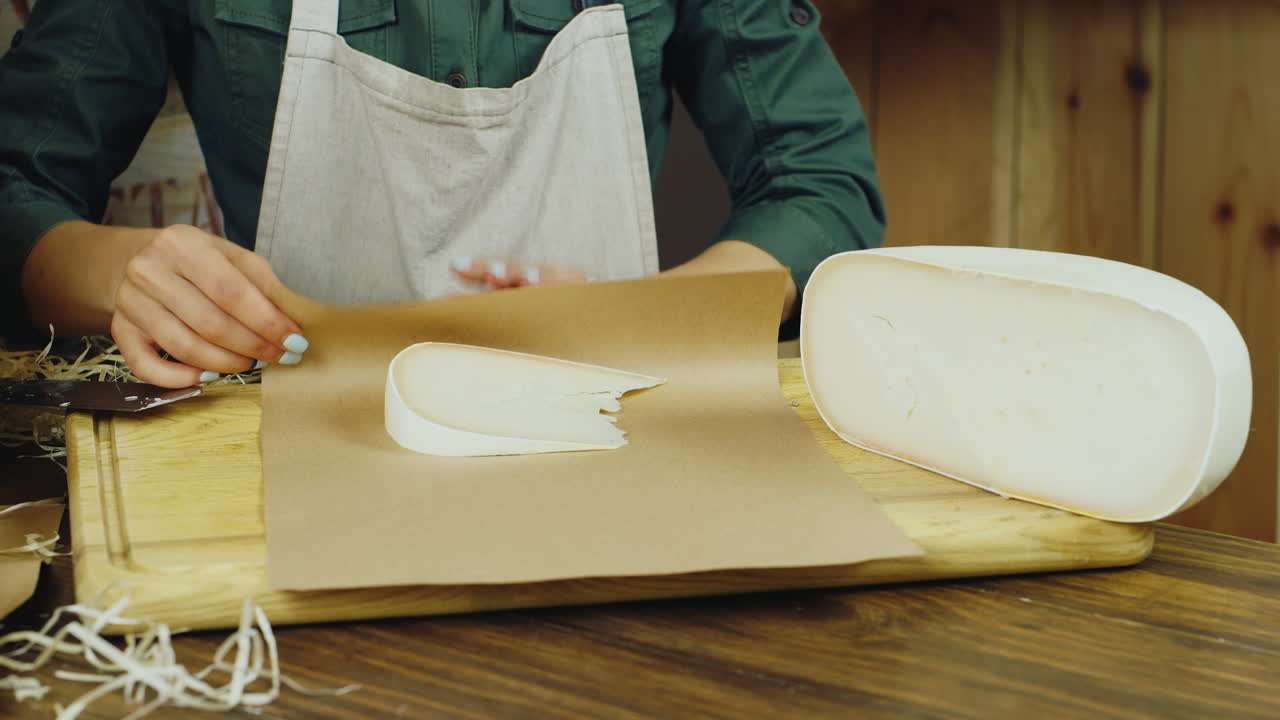 판매자 손에 치즈 한 조각이 종이 포장 hd 비디오에 포장되어 있습니다.