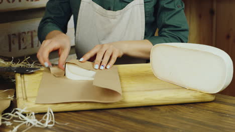 el vendedor entrega un trozo de queso empaquetado en papel de video hd