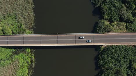 Aerial approaching motor vehicles driving bridge road over river
