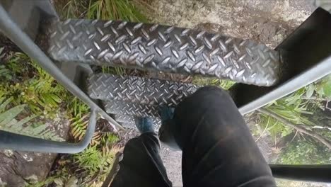 POV-of-a-man-climbing-down-a-metal-ladder-in-dirty-hiking-cloths