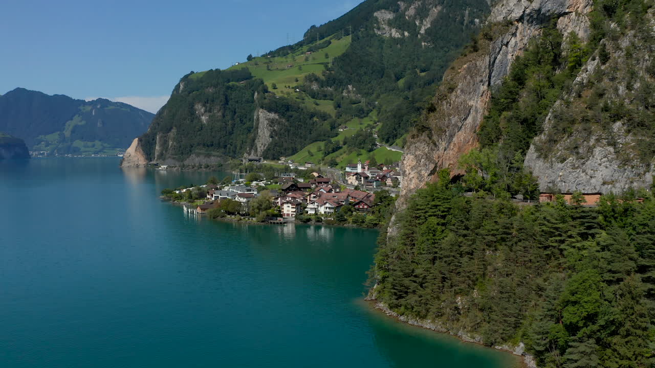 Aerial shot of the lakeside village Sisikon embedded in rocks located at the Lake Lucerne on a sunny summer day.