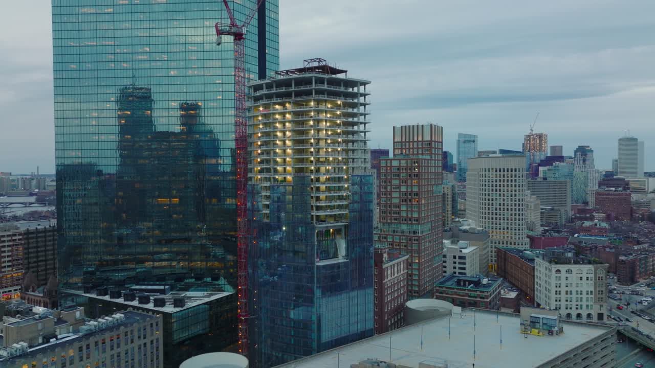 снимок стройплощадки высокого здания. башенный кран и современный небоскреб с глянцевым фасадом. бостон, сша