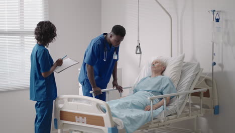 a black doctor and a nurse interview an elderly patient a pensioner in the hospital and take care of his health