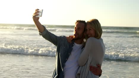 Couple-taking-selfie-on-mobile-phone-at-beach