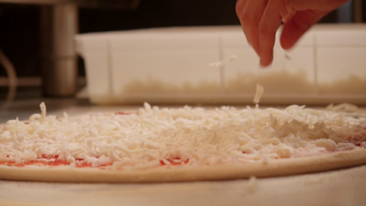 테이블 위 에 피자 반죽 을 준비 하고 있다. 위 에 치즈 를 뿌려라