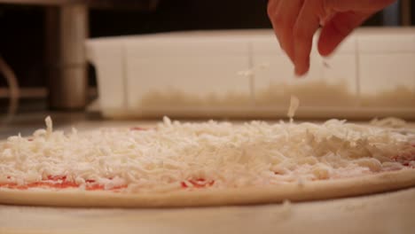 la preparación de la masa de pizza en la mesa. salpicar el queso en la parte superior