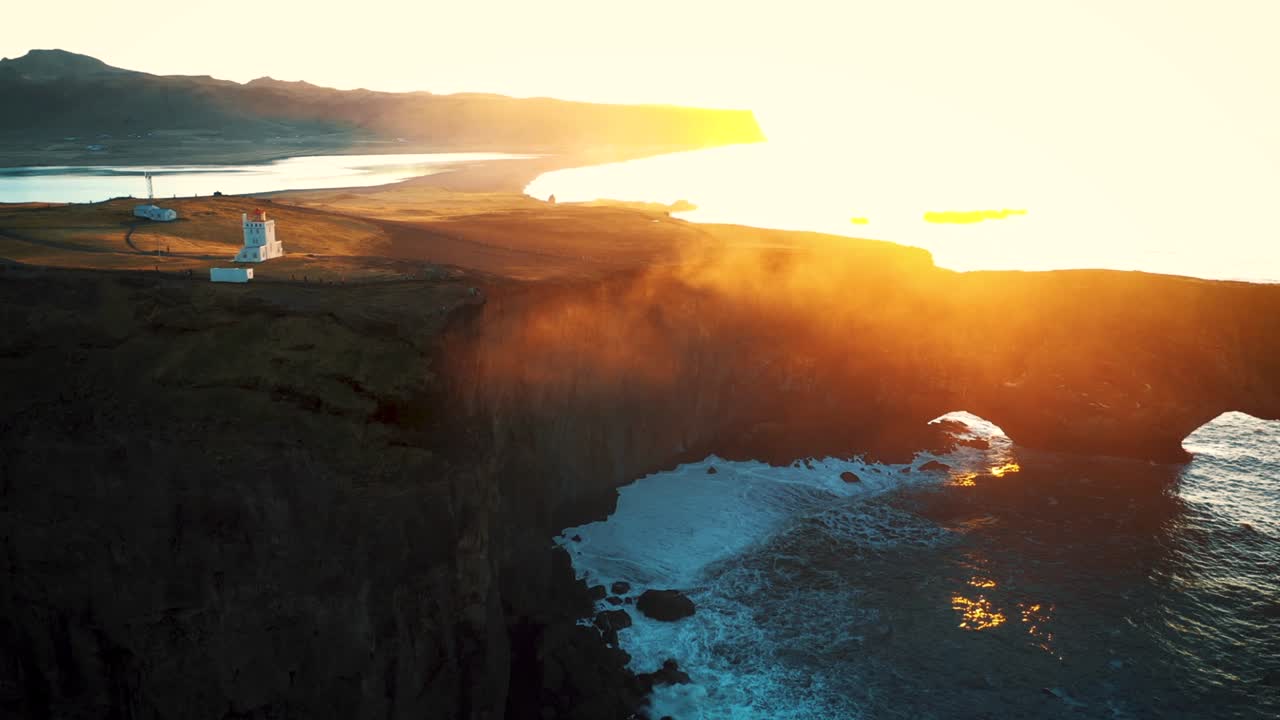 amazing sunset on the rocky beach with arch cliff and lighthouse in Iceland
