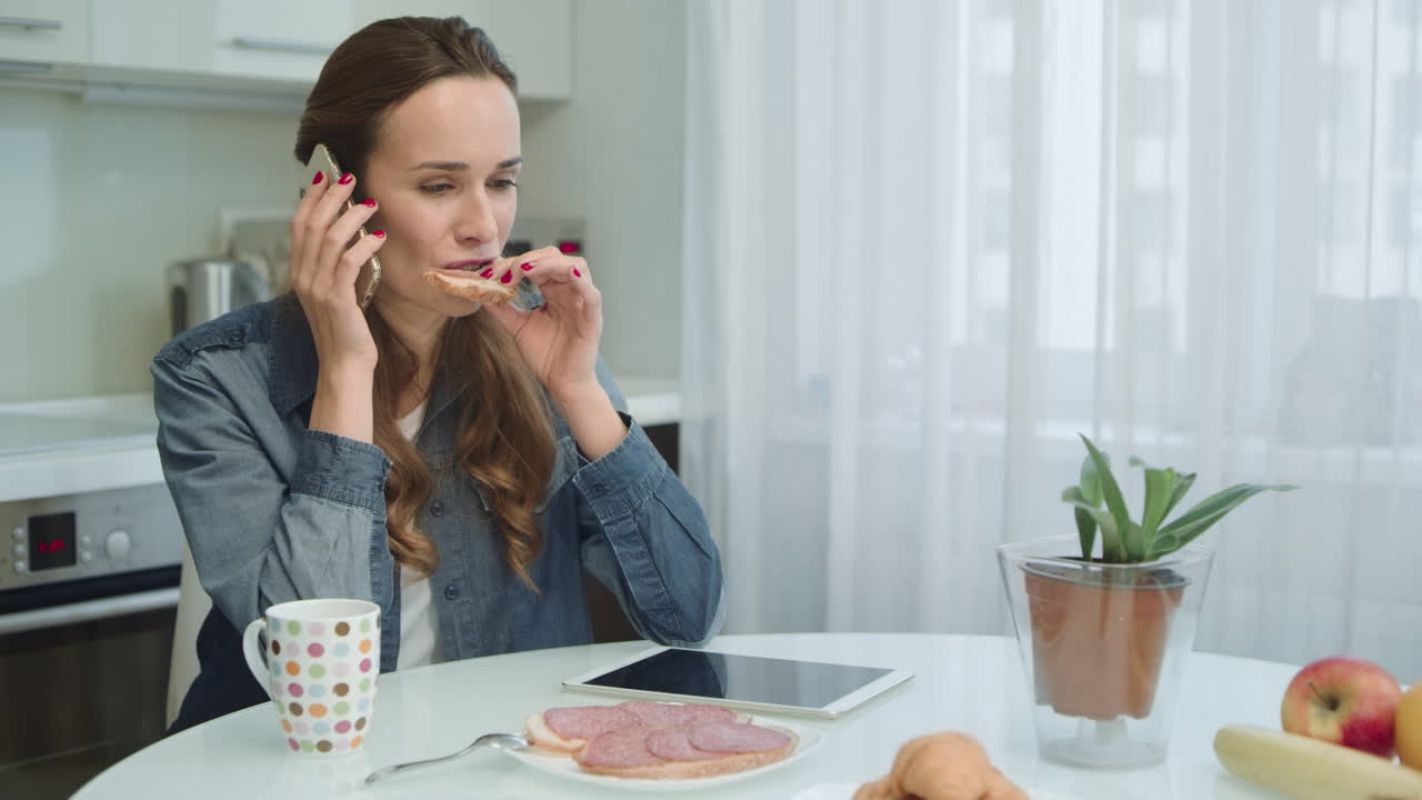 mujer sonriente hablando por teléfono. ama de casa comiendo sándwich y café en casa.