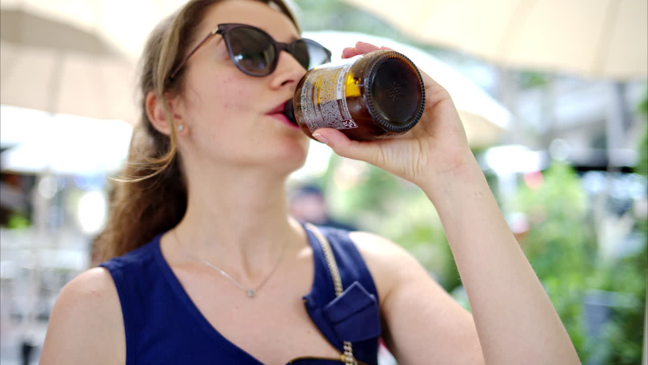 Woman drinking kombucha at a terrace, slow motion