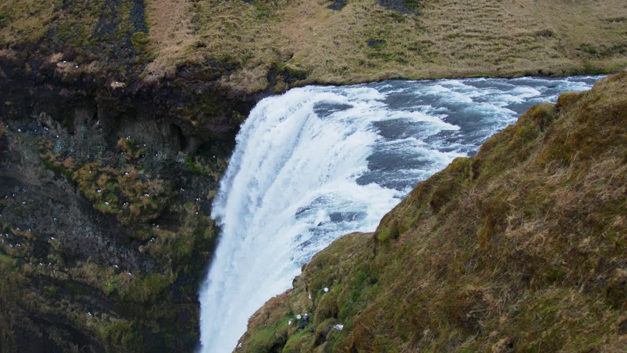 vista superior de la cascada de skogafoss en islandia, el agua fluye por el borde