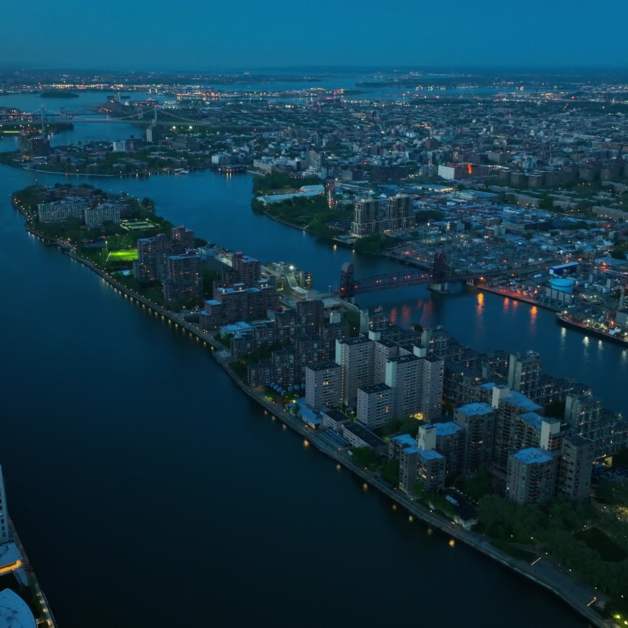 Evening slowly falling on New York city. Top view on the river and buildings with luminous lights