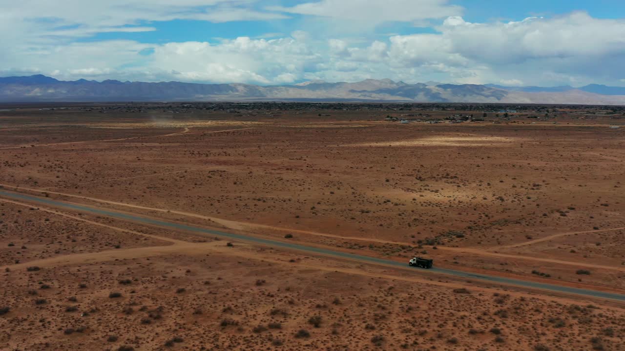 un camión solitario conduce por el medio del desierto de mojave - movimiento aéreo dinámico y vista panorámica