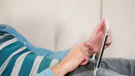 un hombre de negocios casual usando una tableta en el sofá.