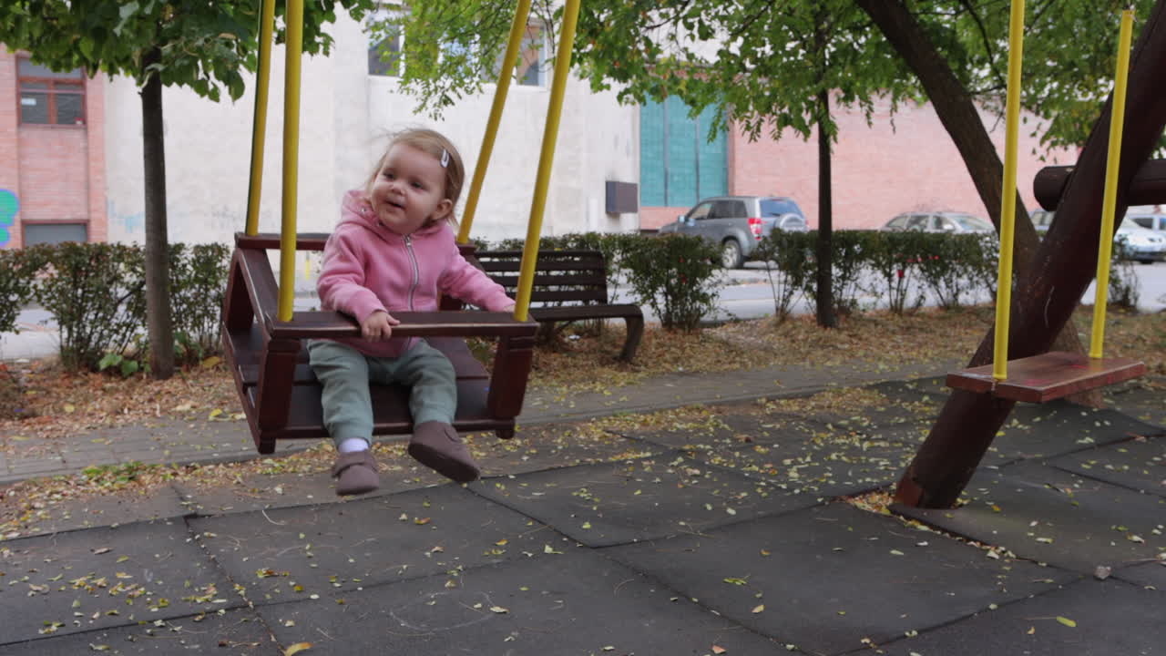 un niño pequeño lindo balanceándose en un columpio de madera en el parque de la ciudad