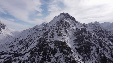 Stunning-rugged-Andorra-mountain-range-with-snow,-trees-and-heavy-clouds