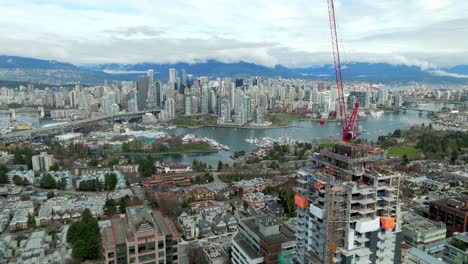Broadway and Granville, Vancouver, Canada - A Skyscraper Under Construction Towers Over a Vibrant City Skyline, Marina, and Distant Mountains - Aerial Drone Shot