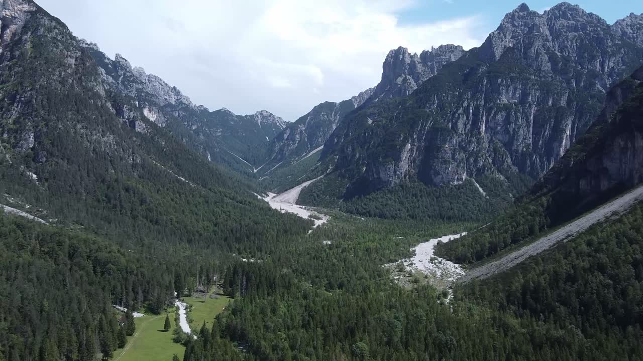 Paesaggio iconico delle Alpi con boschi e catene montuose, vista aerea.