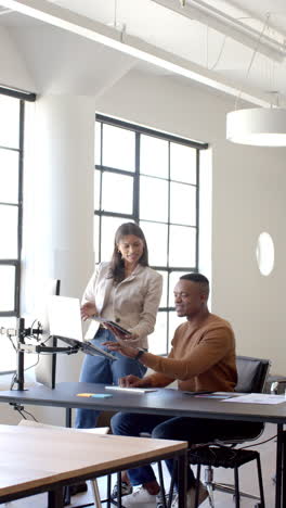 vertical video: collaborating in modern office, colleagues using tablet and desktop discussing proje